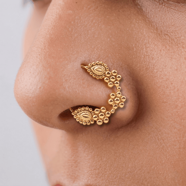 Close-up of gold nose ring on skin showing detailed craftsmanship