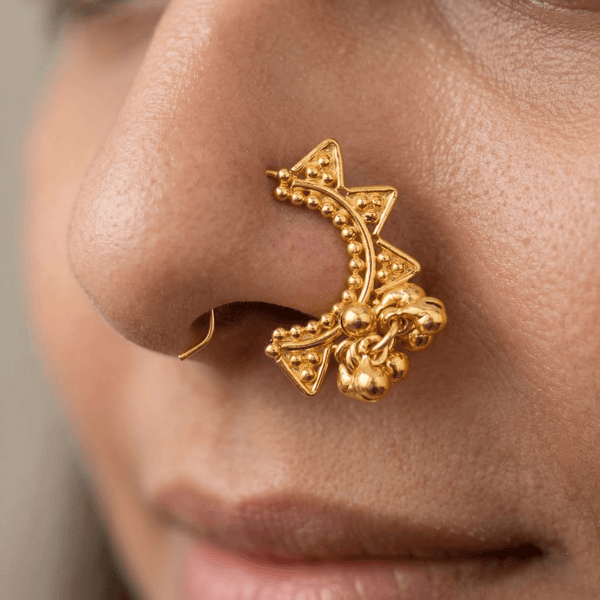 Close-up of gold-tone star-shaped nose ring on white background
