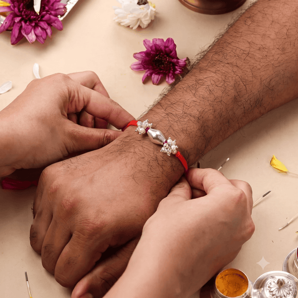 Handcrafted silver Dholki bead Rakhi with ruby and pearl accents