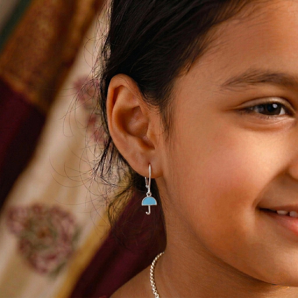 Close-up of silver enamel umbrella earrings worn by a girl