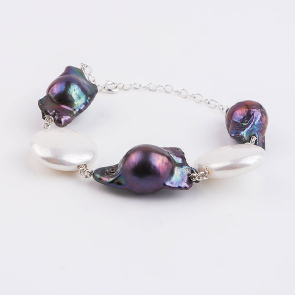 Flat-lay of pearl silver Ganthan bracelet on soft fabric with natural light and accessories