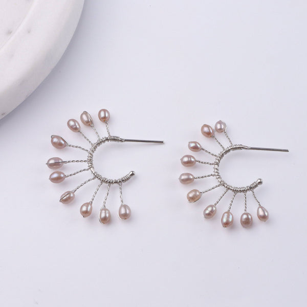 Angled view of Rice Pearl Snowflake Hoops in 92.5 sterling silver featuring delicate rice pearl and snowflake detailing