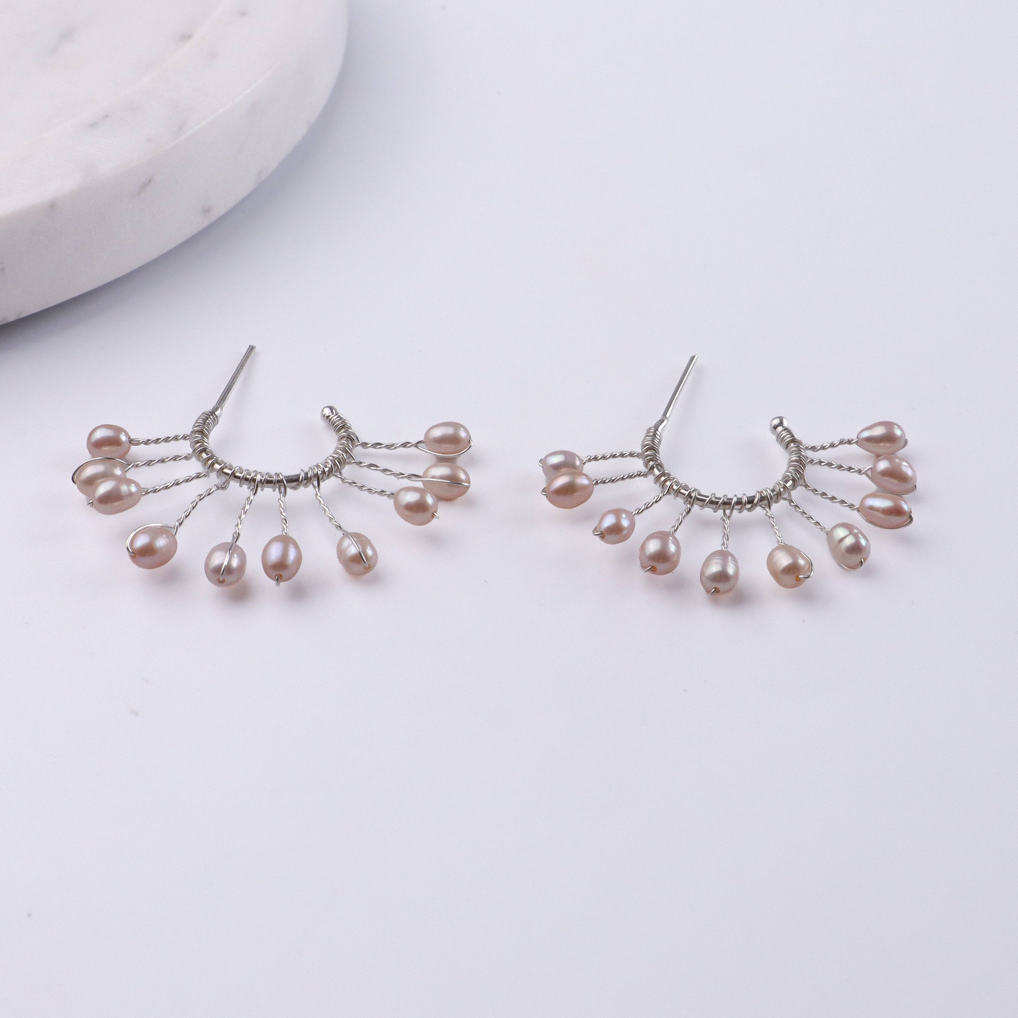 Flat-lay of Rice Pearl Snowflake Hoops with natural pearls and complementary handcrafted silver jewelry