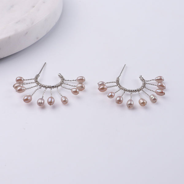 Flat-lay of Rice Pearl Snowflake Hoops with natural pearls and complementary handcrafted silver jewelry
