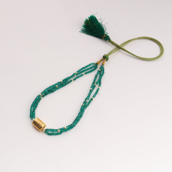 Close-up of green onyx beaded necklace with gold clasp and tassel detail