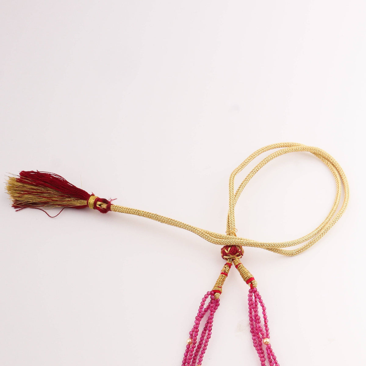 Close-up of pink beaded necklace with gold accents and carved pendant