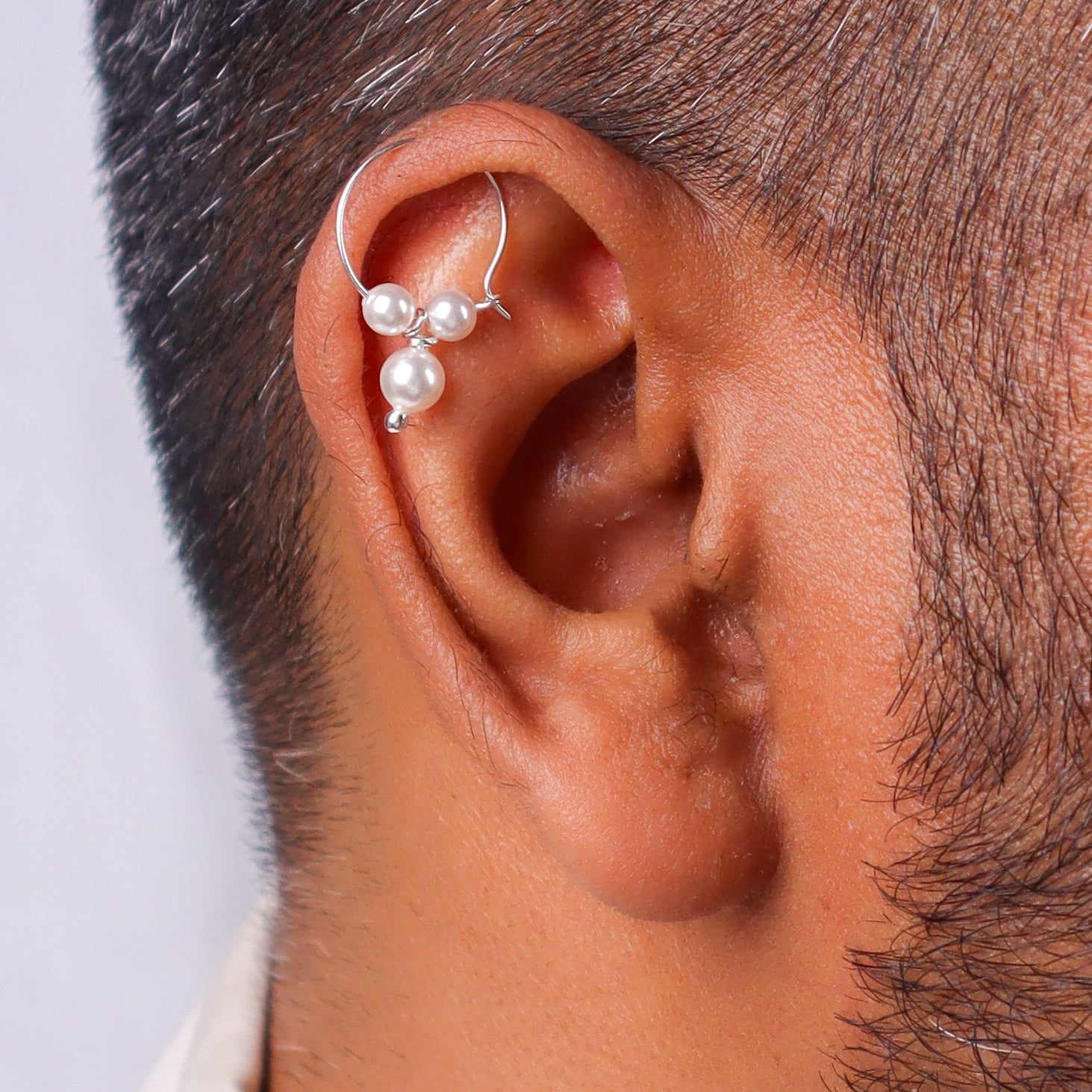 Silver pearl Bhikbali earring with three white pearls on a man's ear