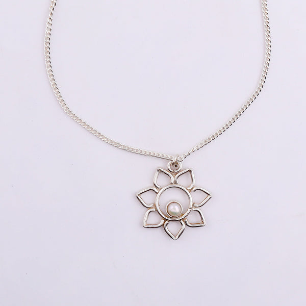 Close-up of silver chain necklace with flower pendant and pearl
