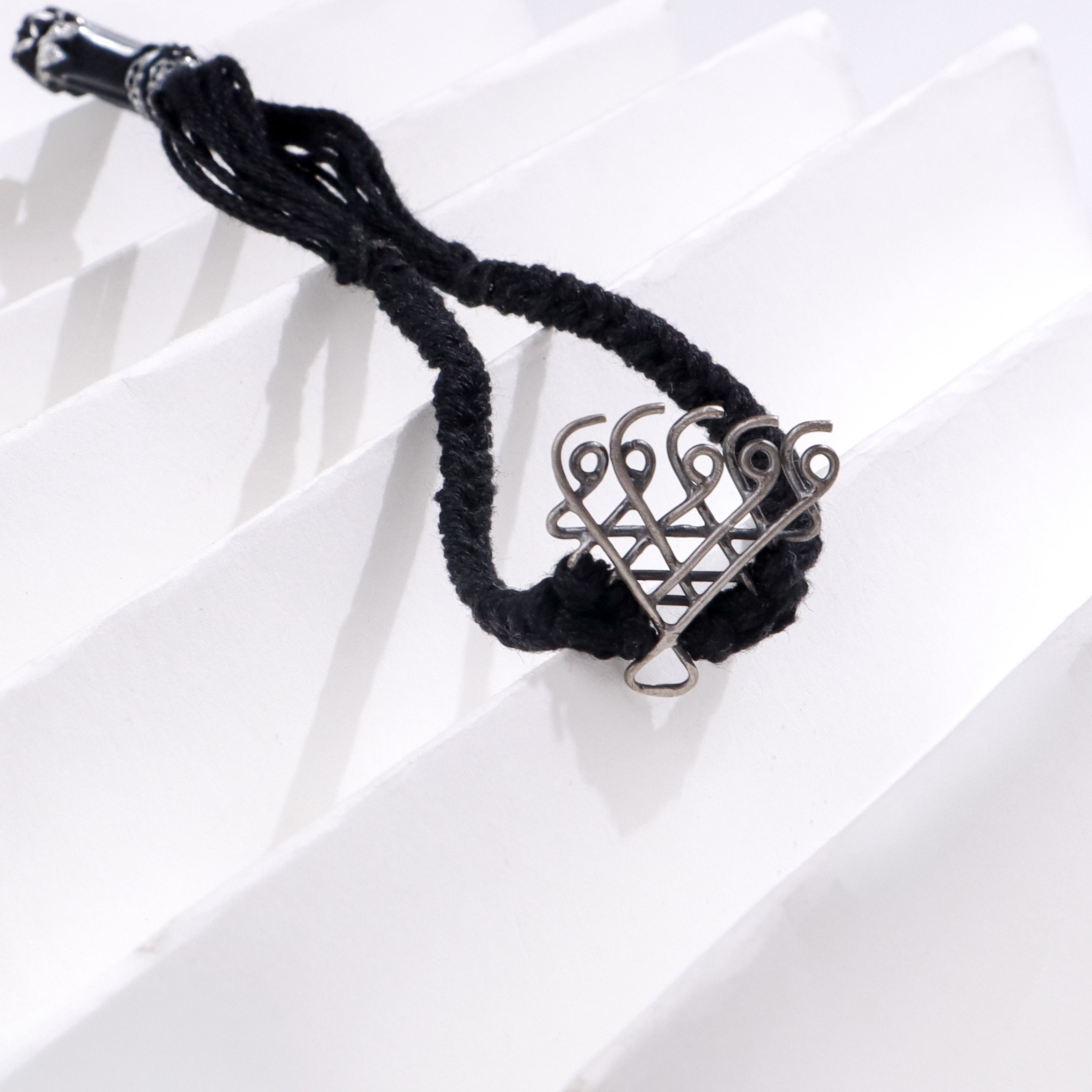Silver Saraswati bracelet small with black thread on white background