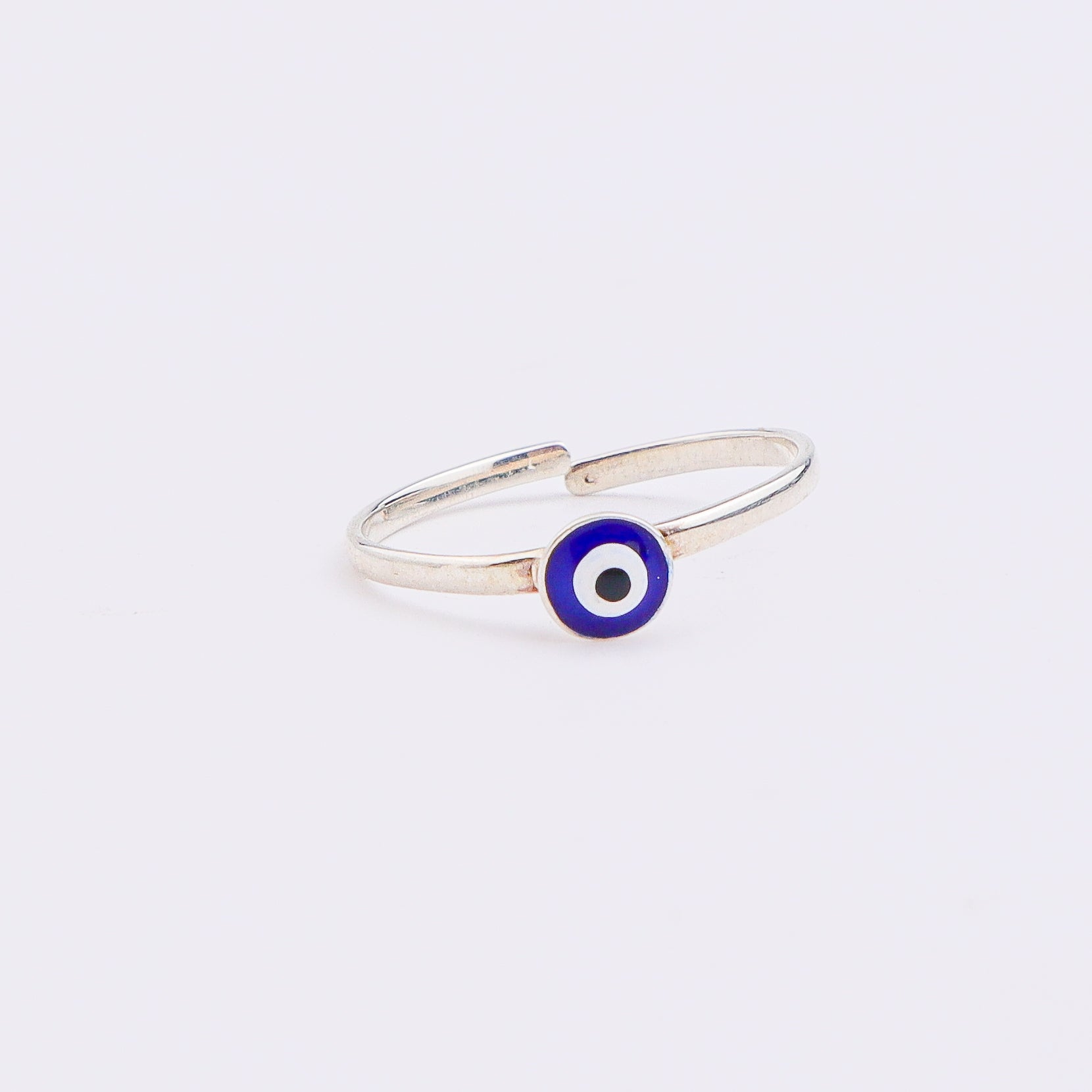 Silver evil eye ring on white surface
