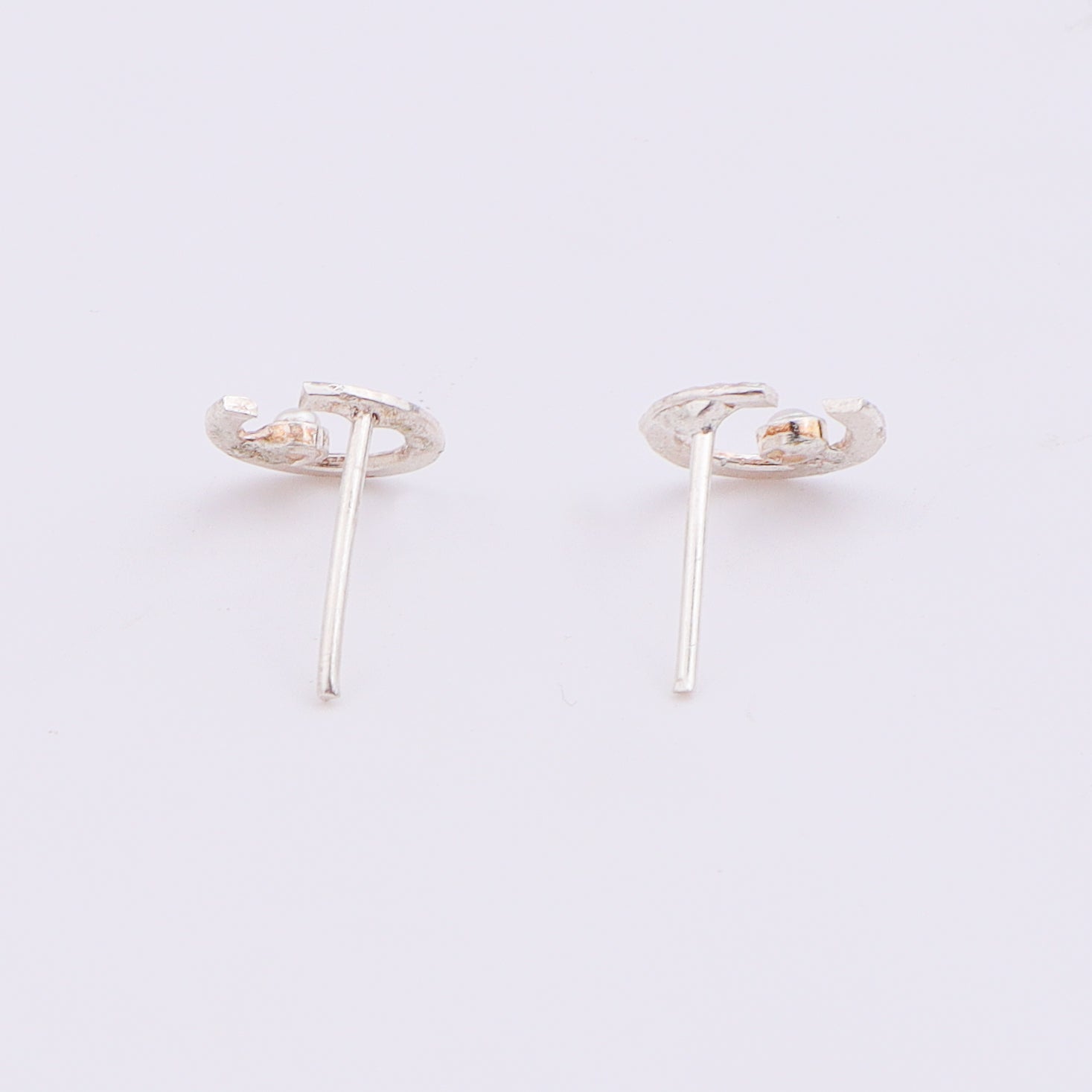 Close-up of silver semi-circle pearl earrings