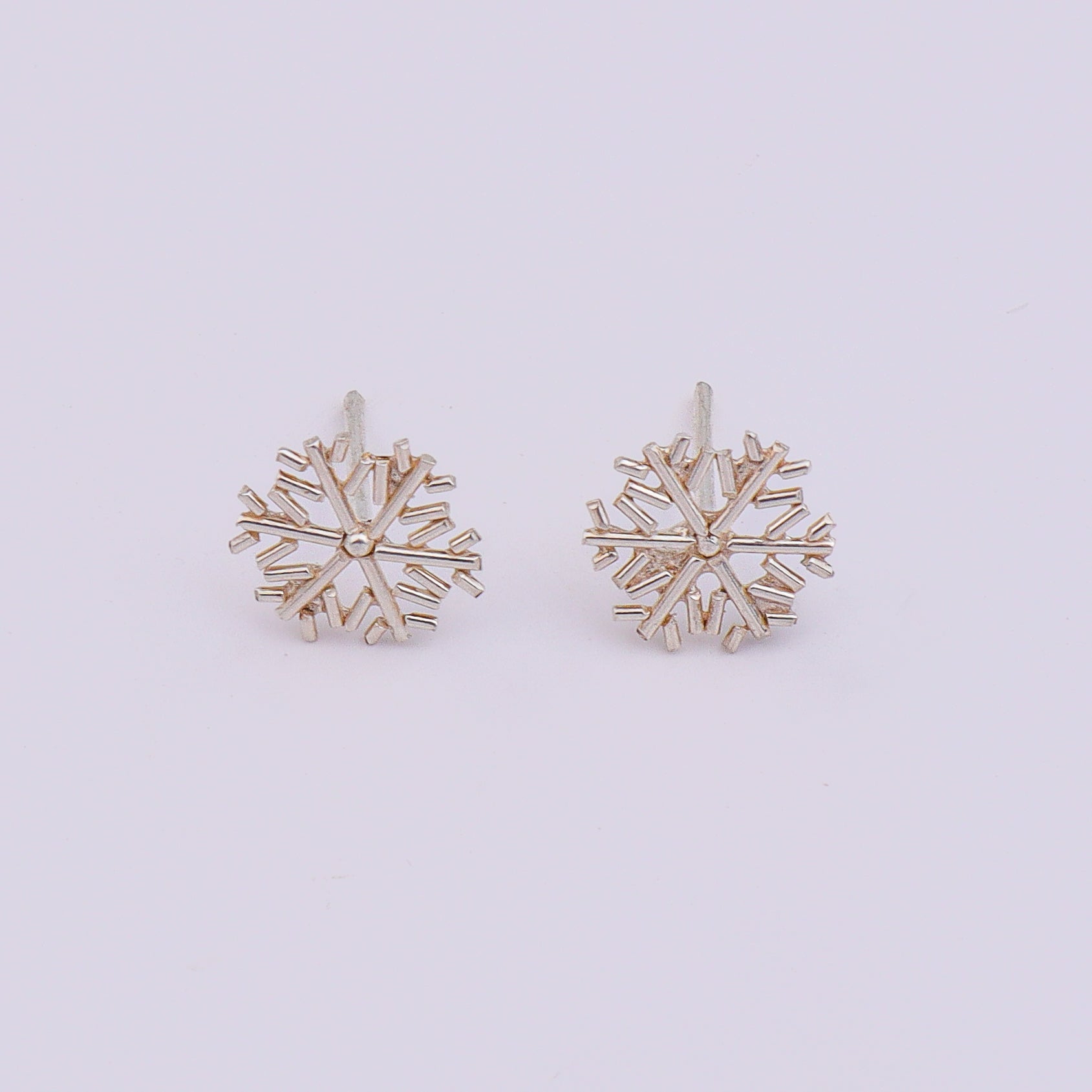 Silver snowflake earrings on display with white backdrop