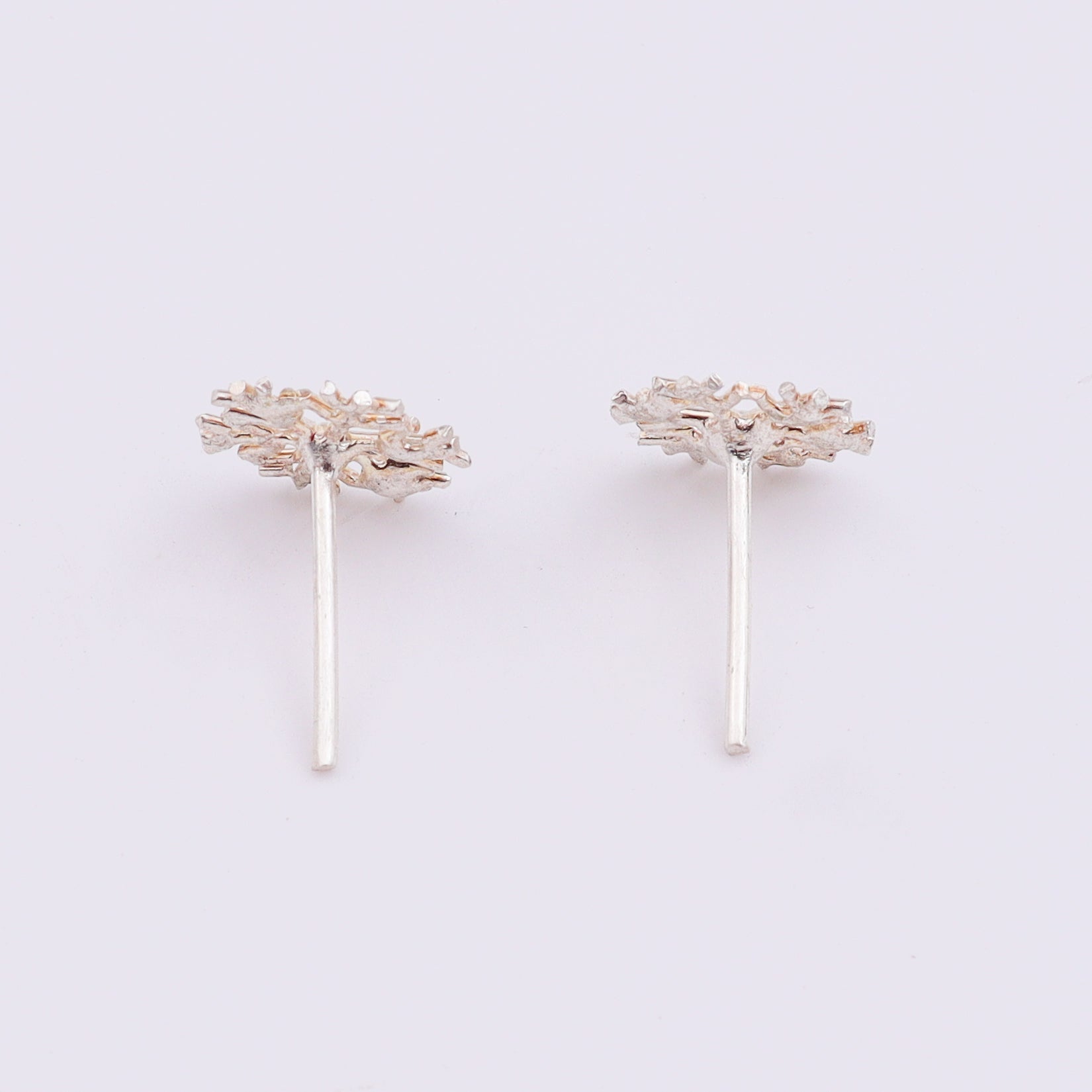 Silver snowflake earrings on white surface with shadow