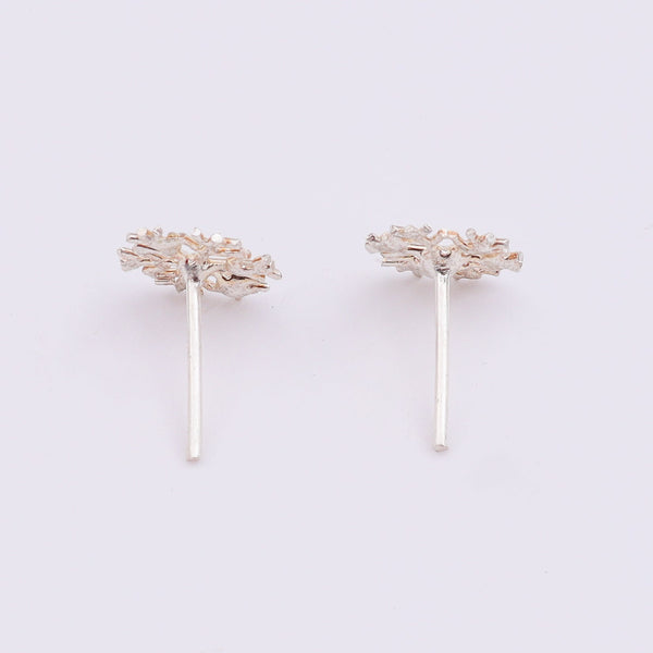 Silver snowflake earrings on white surface with shadow
