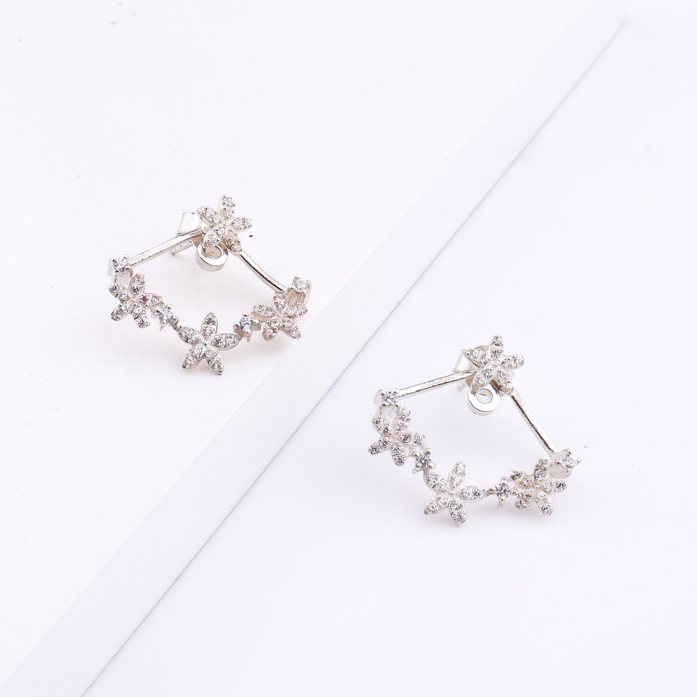 Silver flower vine CZ jacket earrings worn on model's ear