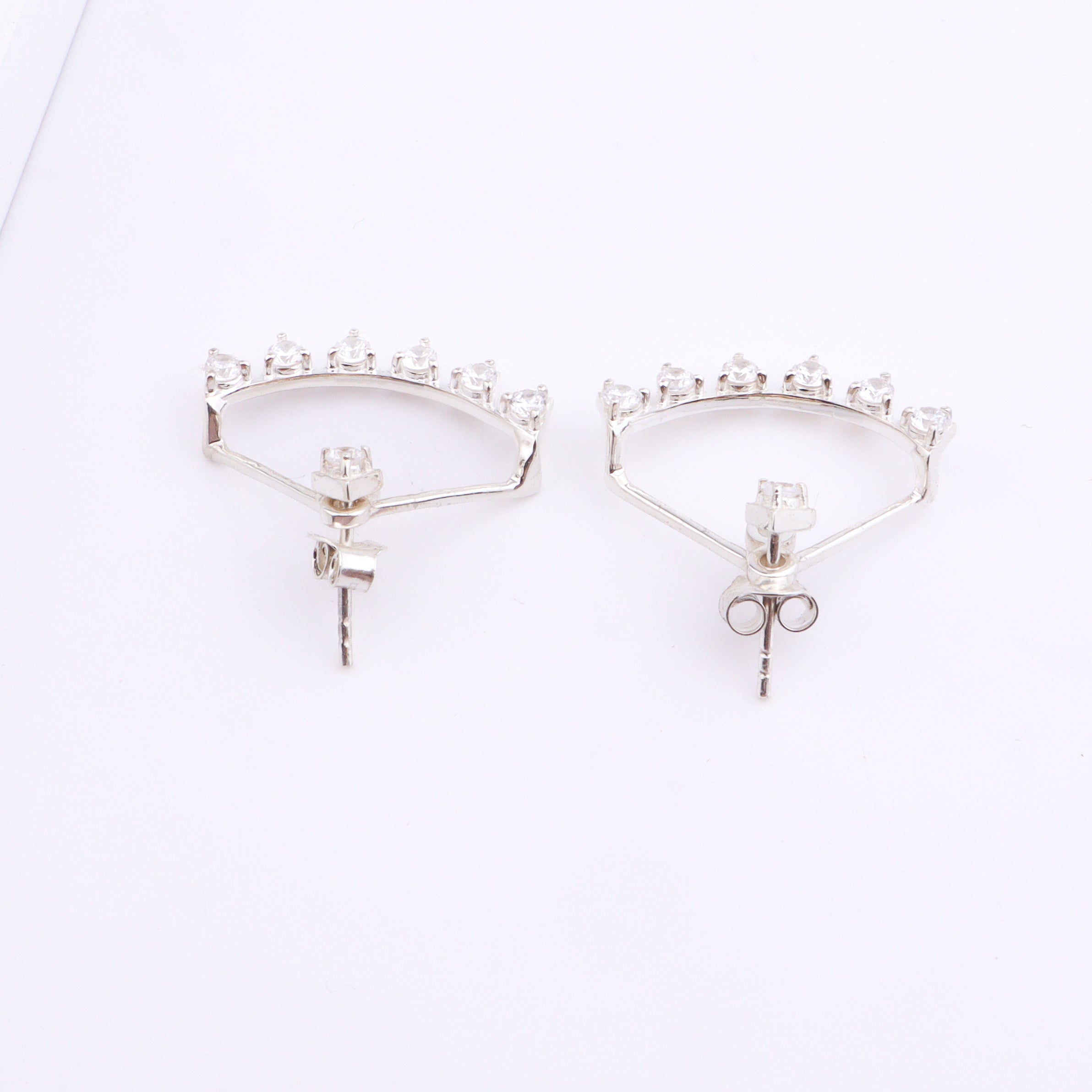 Silver hoop earrings with sparkling stones on white surface