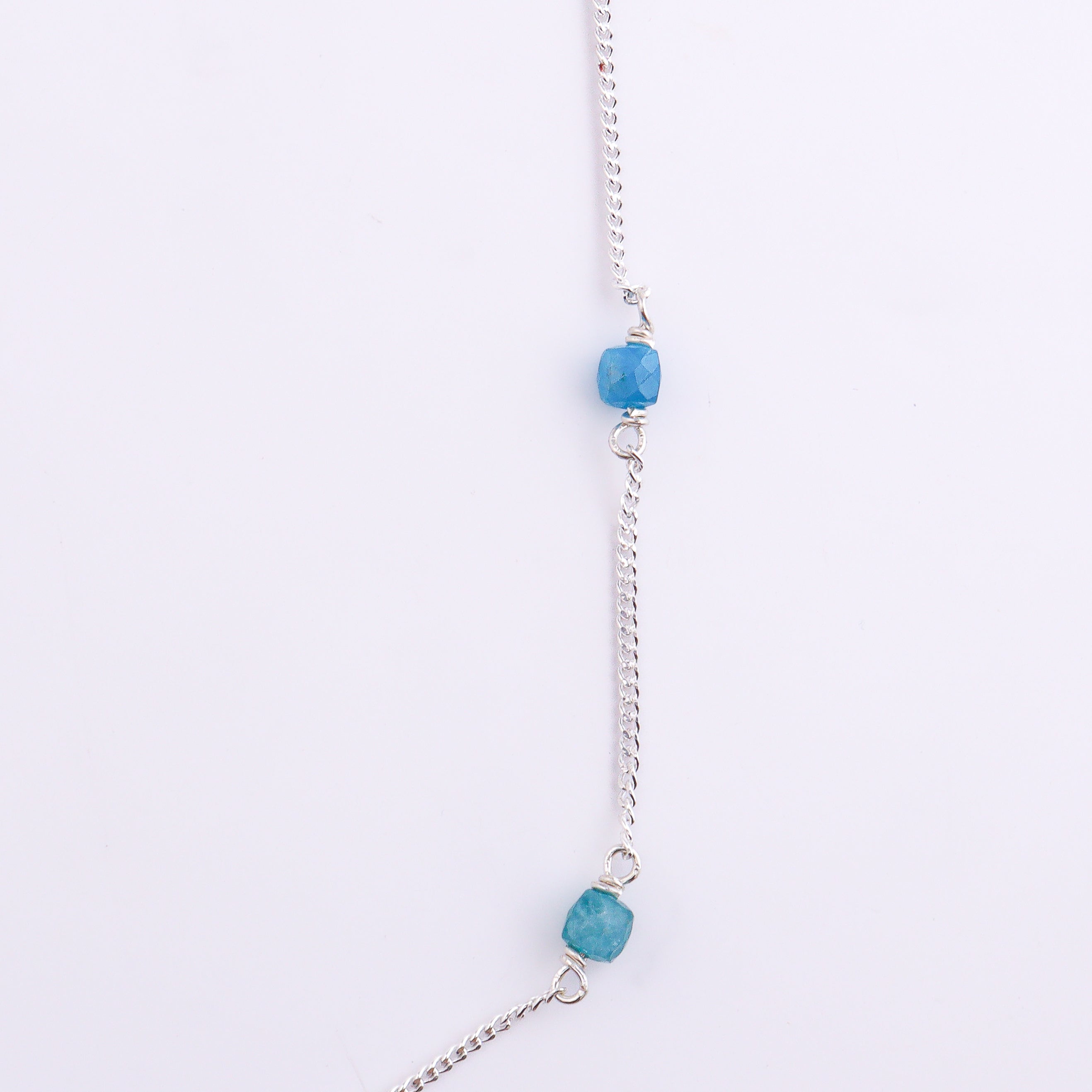 Silver chain with blue apatite gemstone on white background