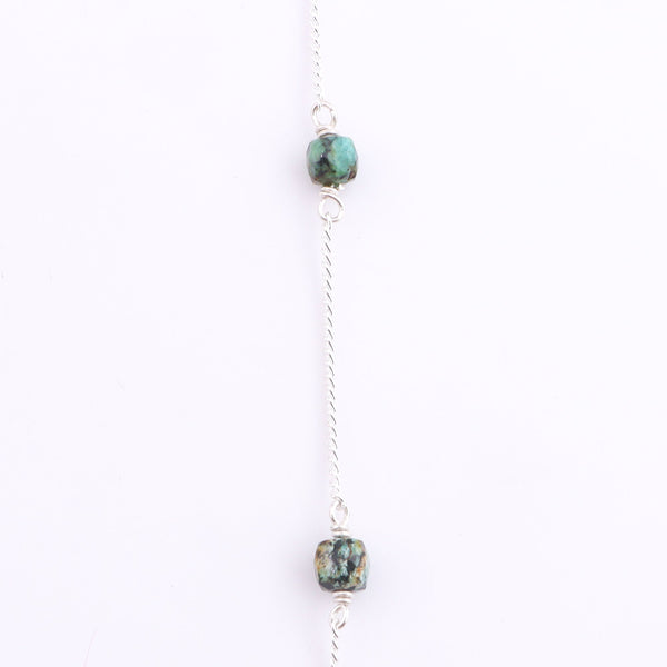 Close-up of silver chain with turquoise bead