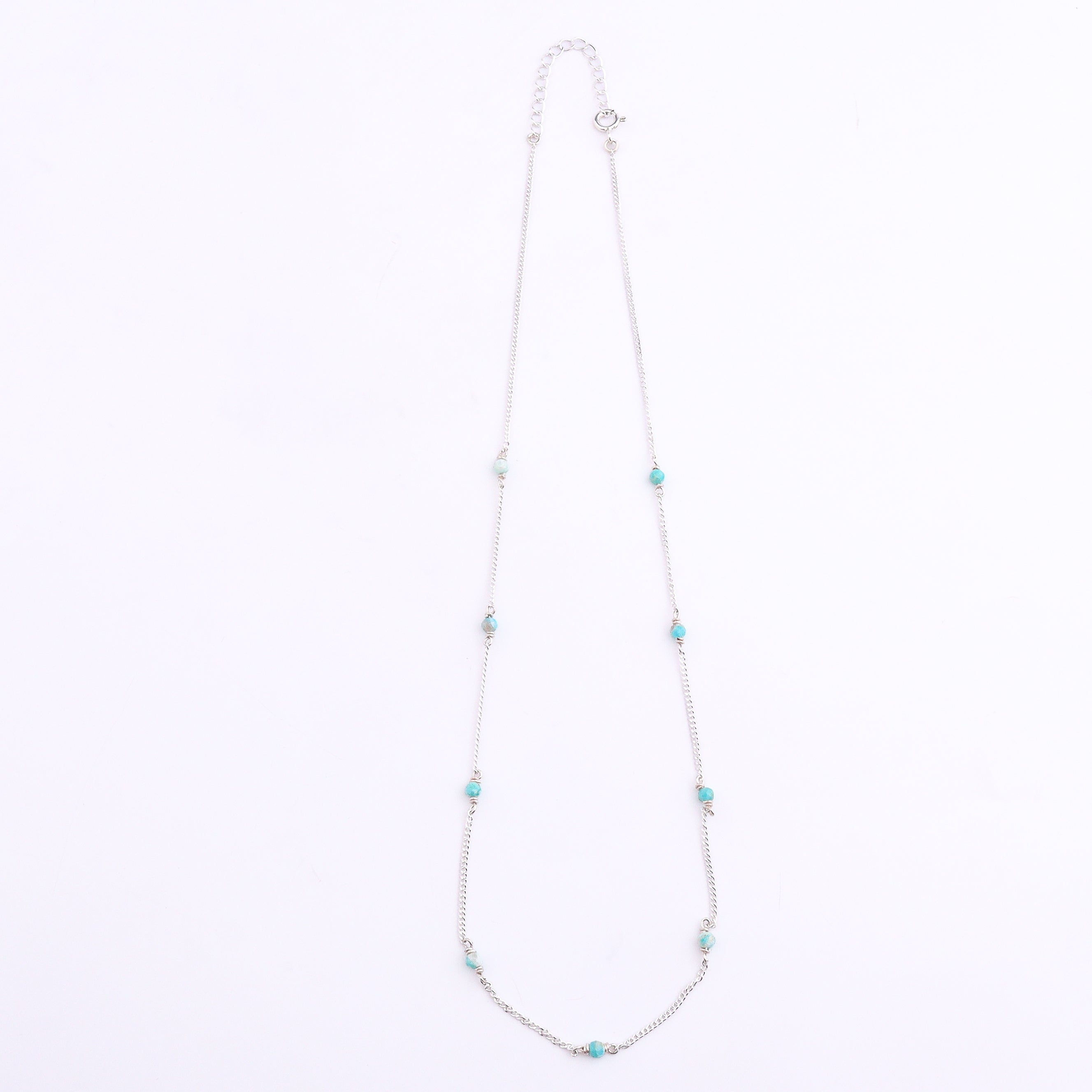 Silver chain with blue jade bead detail on white background