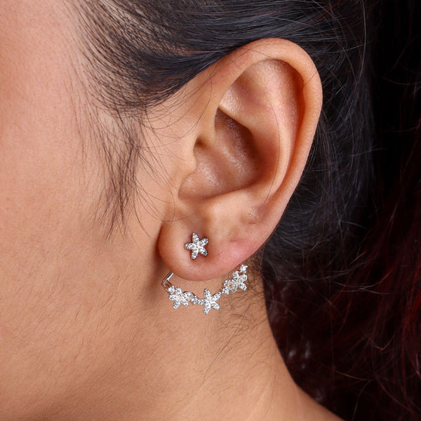 Close-up of silver flower vine CZ jacket earrings on white background