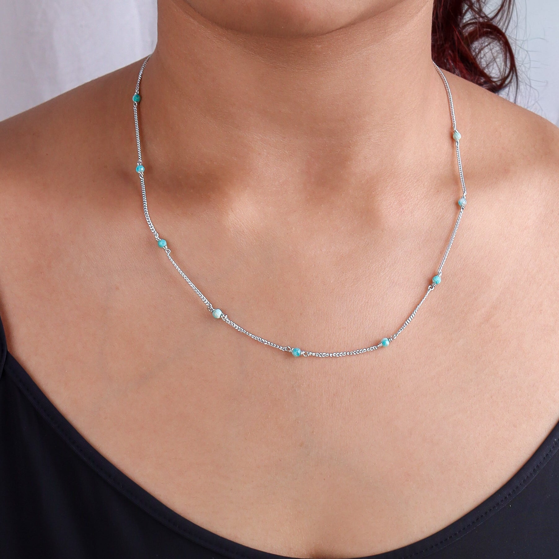 Close-up of silver chain with blue jade beads on model