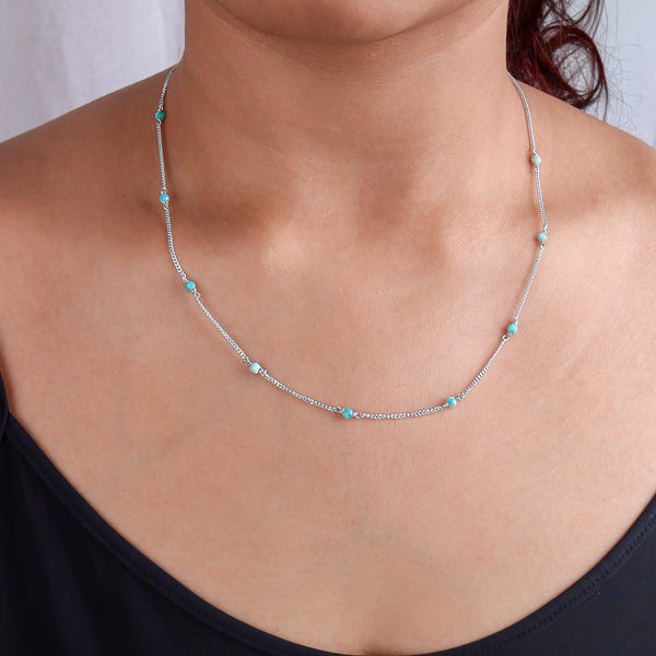 Close-up of silver chain with blue jade beads on model
