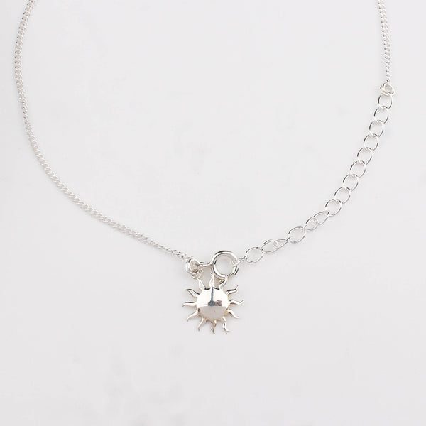 Close-up of silver sun charm anklet detailing