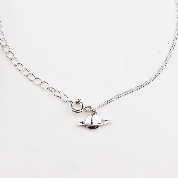 Close-up of silver planet charm anklet detailing