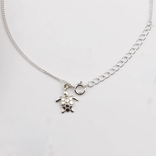 Close-up of silver turtle charm anklet detailing