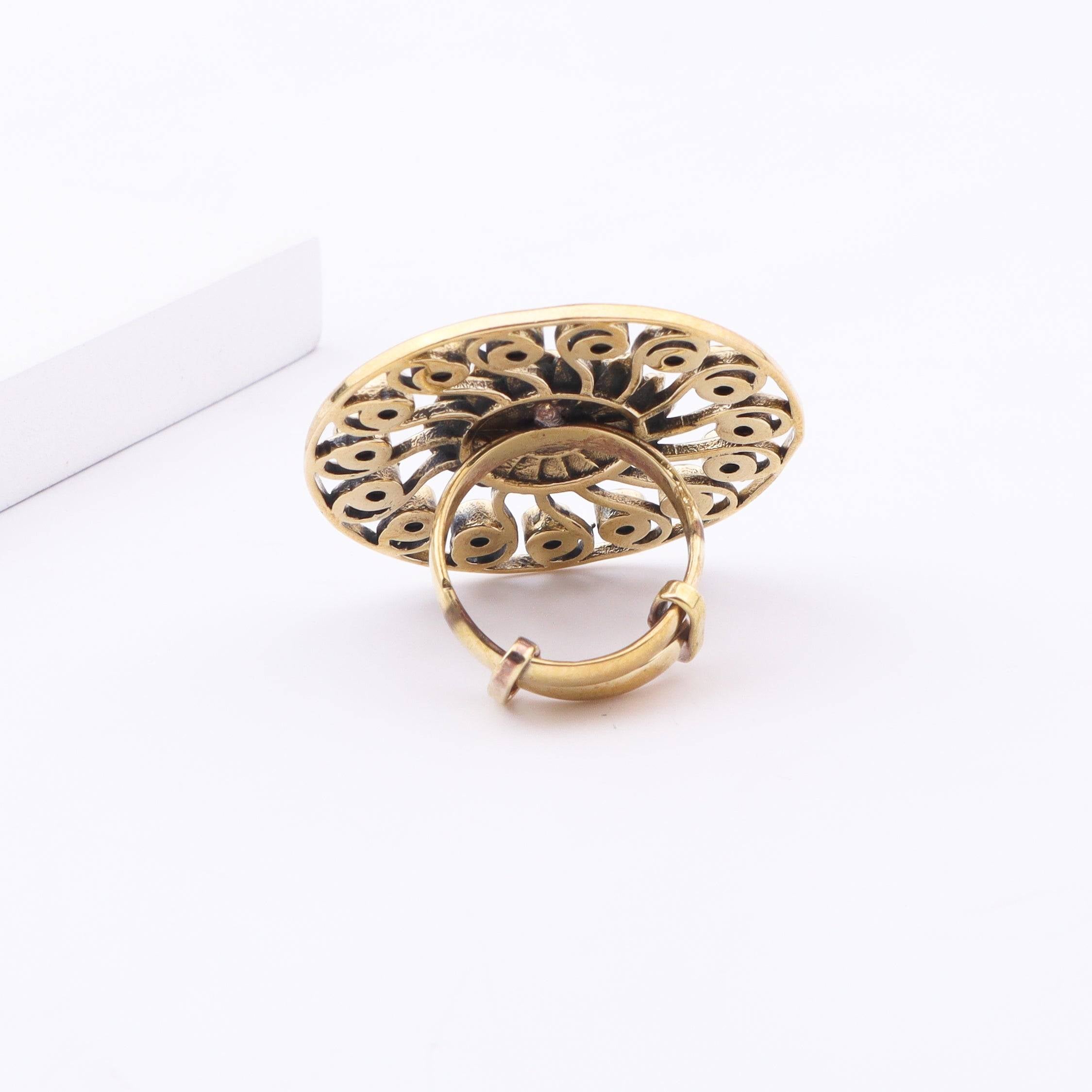 Angled view of a brass fashion ring highlighting its distinctive shape, structure, and polished brass finish