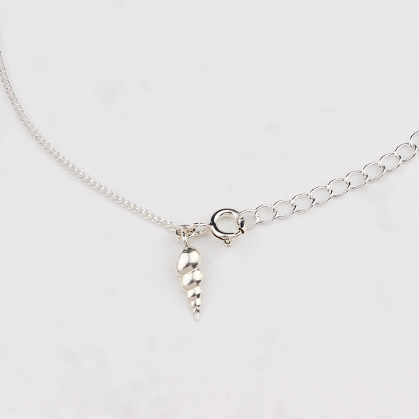 Close-up of silver auger shell charm anklet detailing
