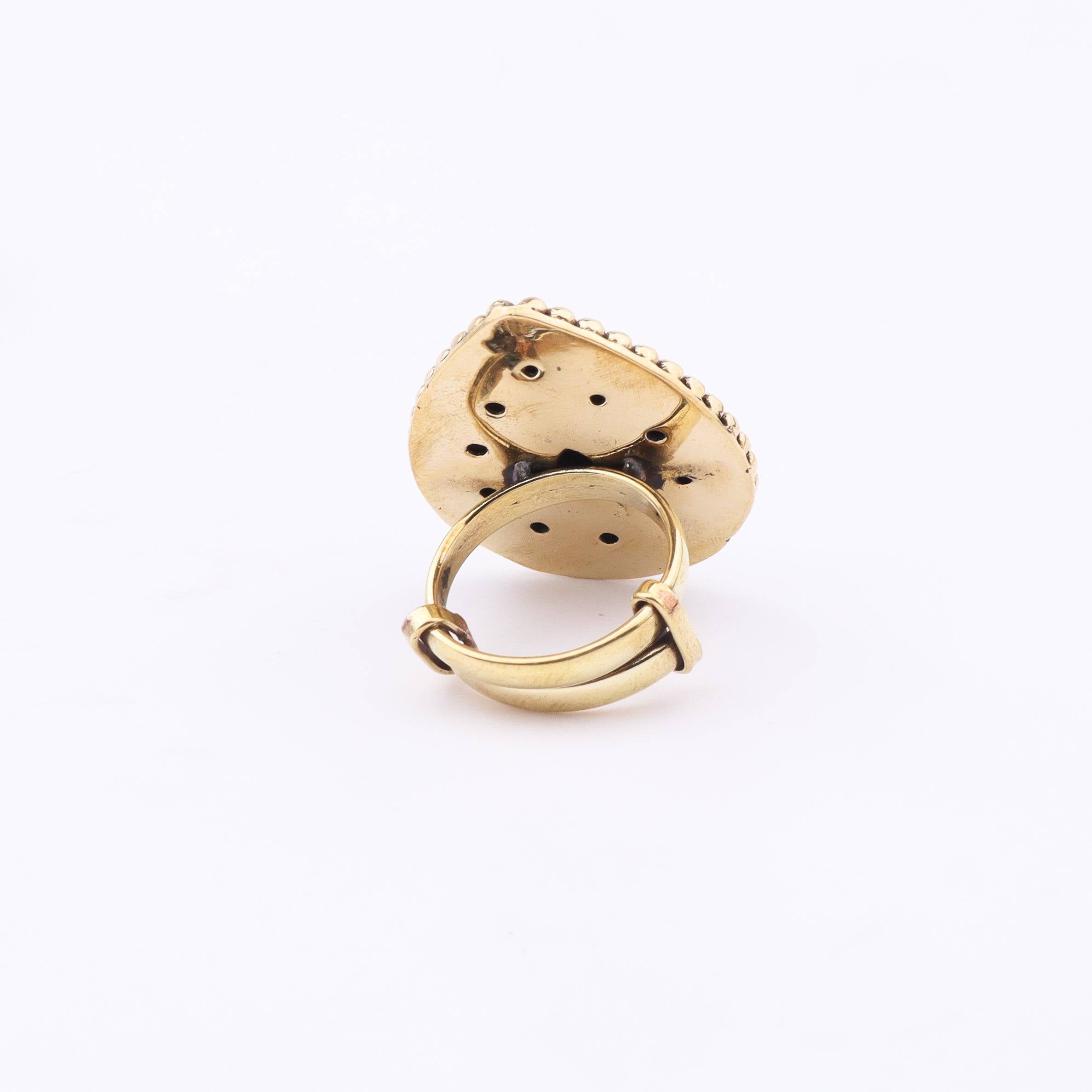 Angled view of a brass fashion ring highlighting its distinctive shape, structure, and polished brass finish