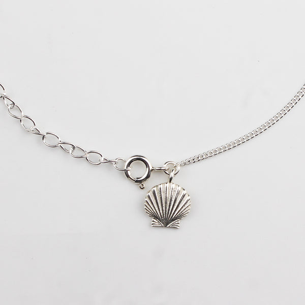 Close-up of silver shell charm anklet detailing