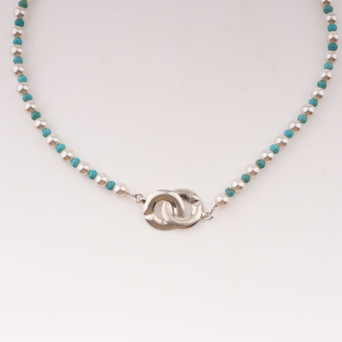 Close-up of pearl and turquoise necklace with infinity lock clasp