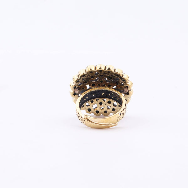 Angled view of a brass fashion ring highlighting its distinctive shape, structure, and polished brass finish