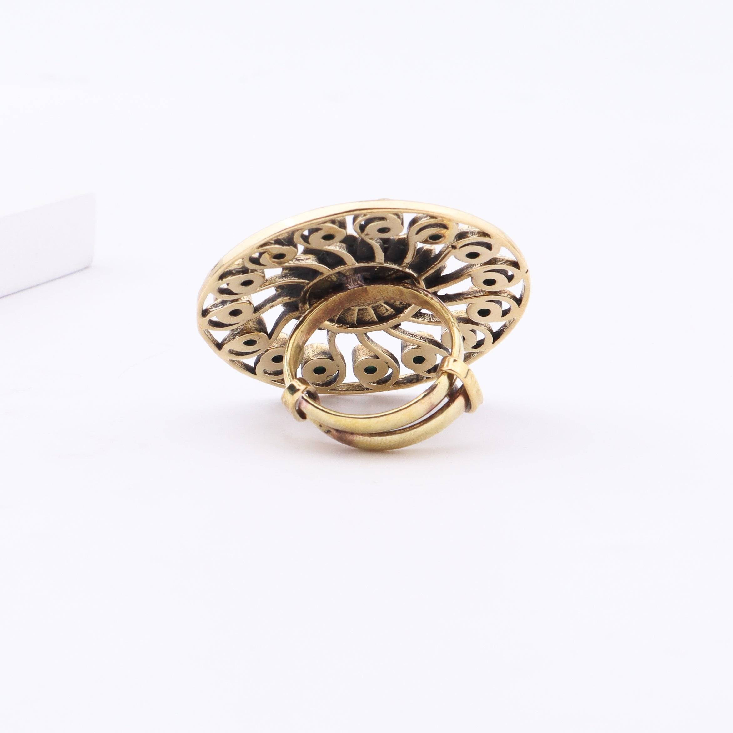 Angled view of a brass fashion ring highlighting its distinctive shape, structure, and polished brass finish