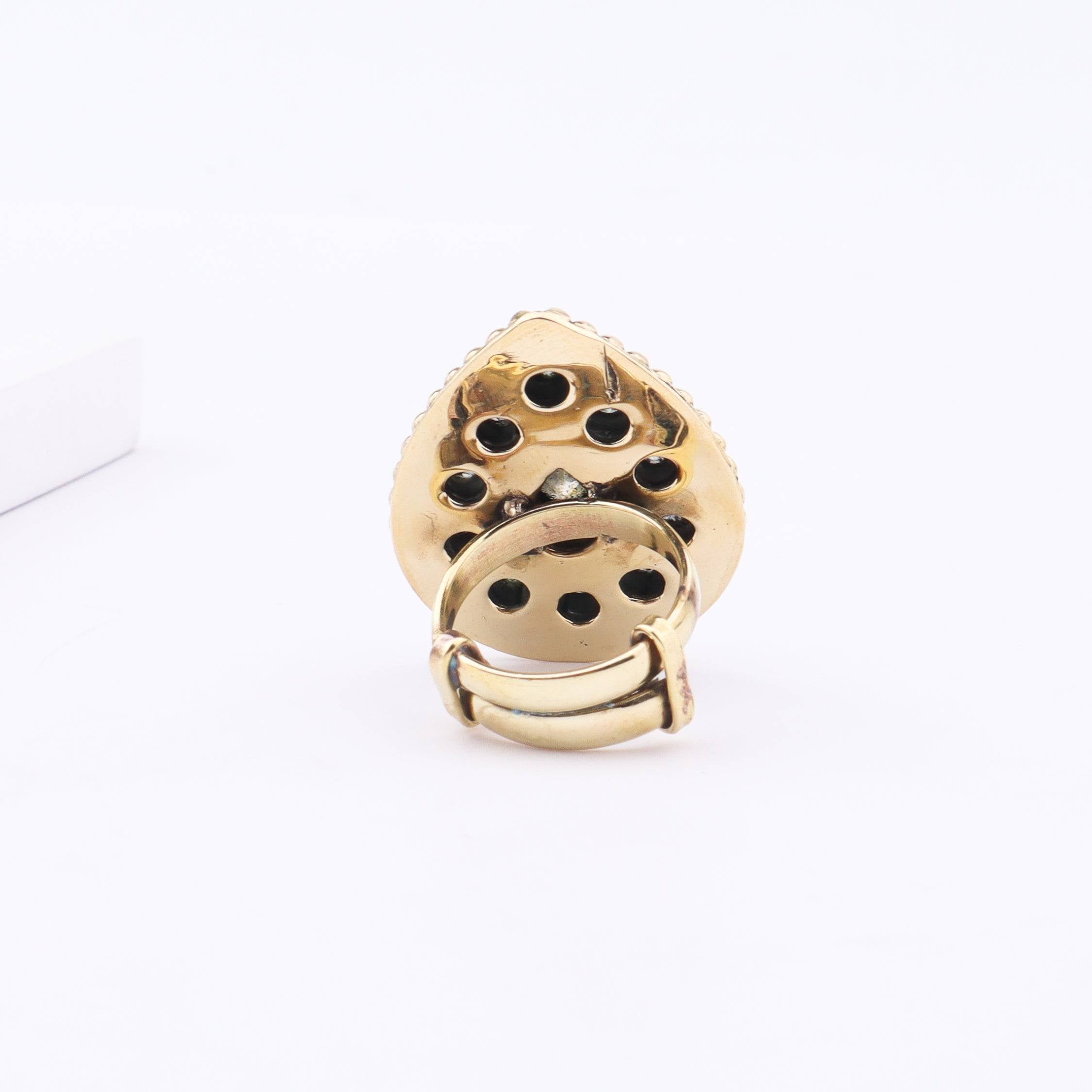 Angled view of a brass fashion ring highlighting its distinctive shape, structure, and polished brass finish