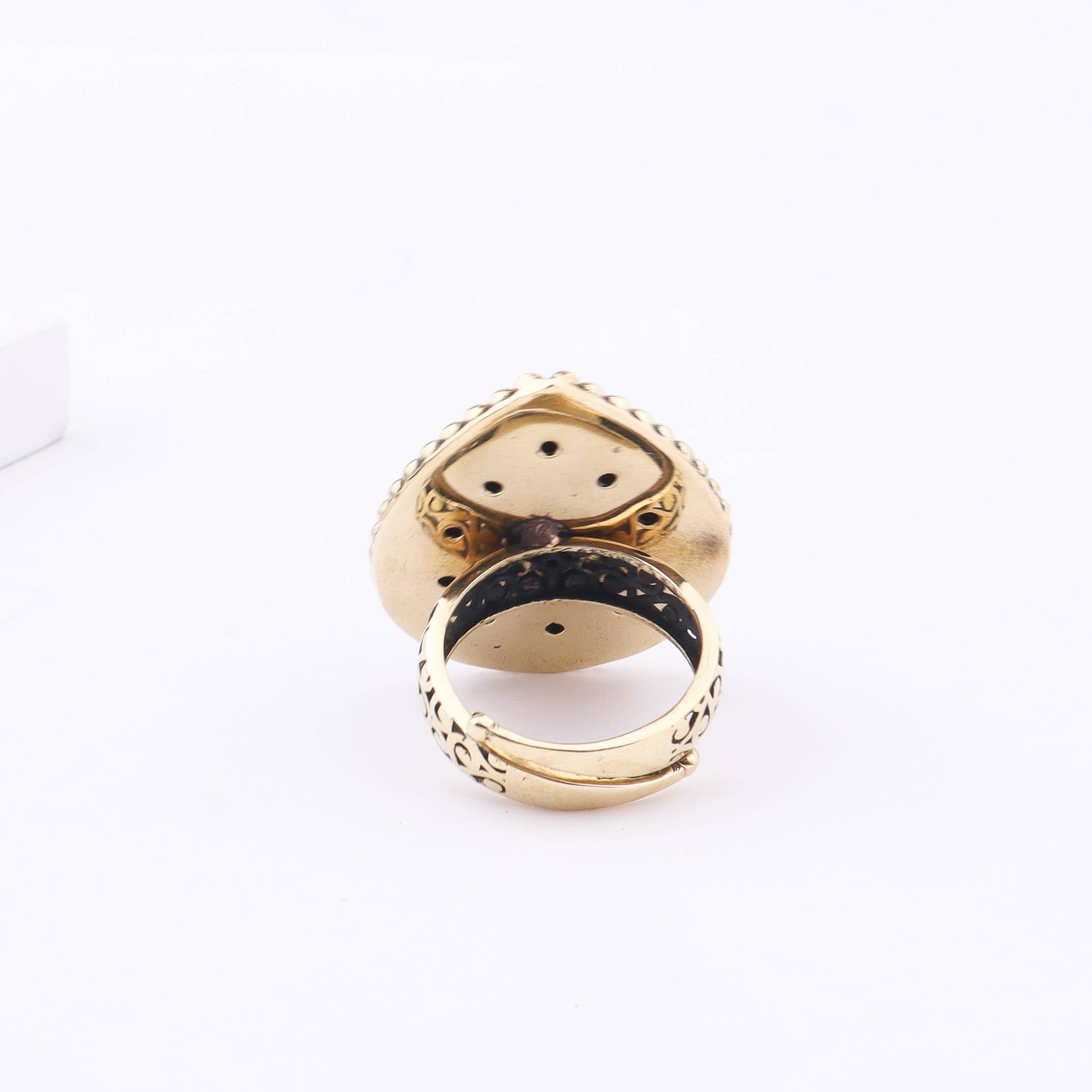 Angled view of a brass fashion ring highlighting its distinctive shape, structure, and polished brass finish