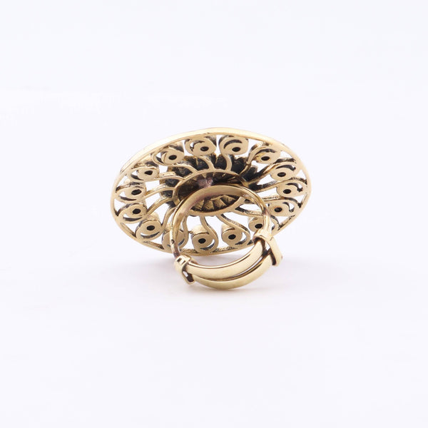 Angled view of a brass fashion ring highlighting its distinctive shape, structure, and polished brass finish
