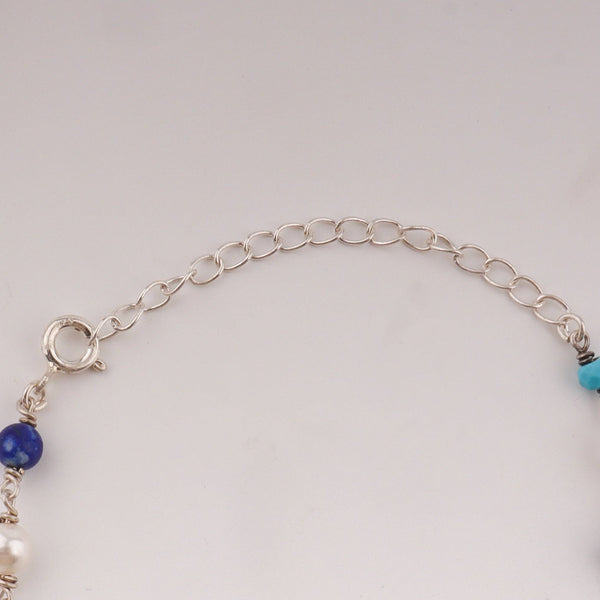 Close-up of silver chain with blue turquoise and white pearls