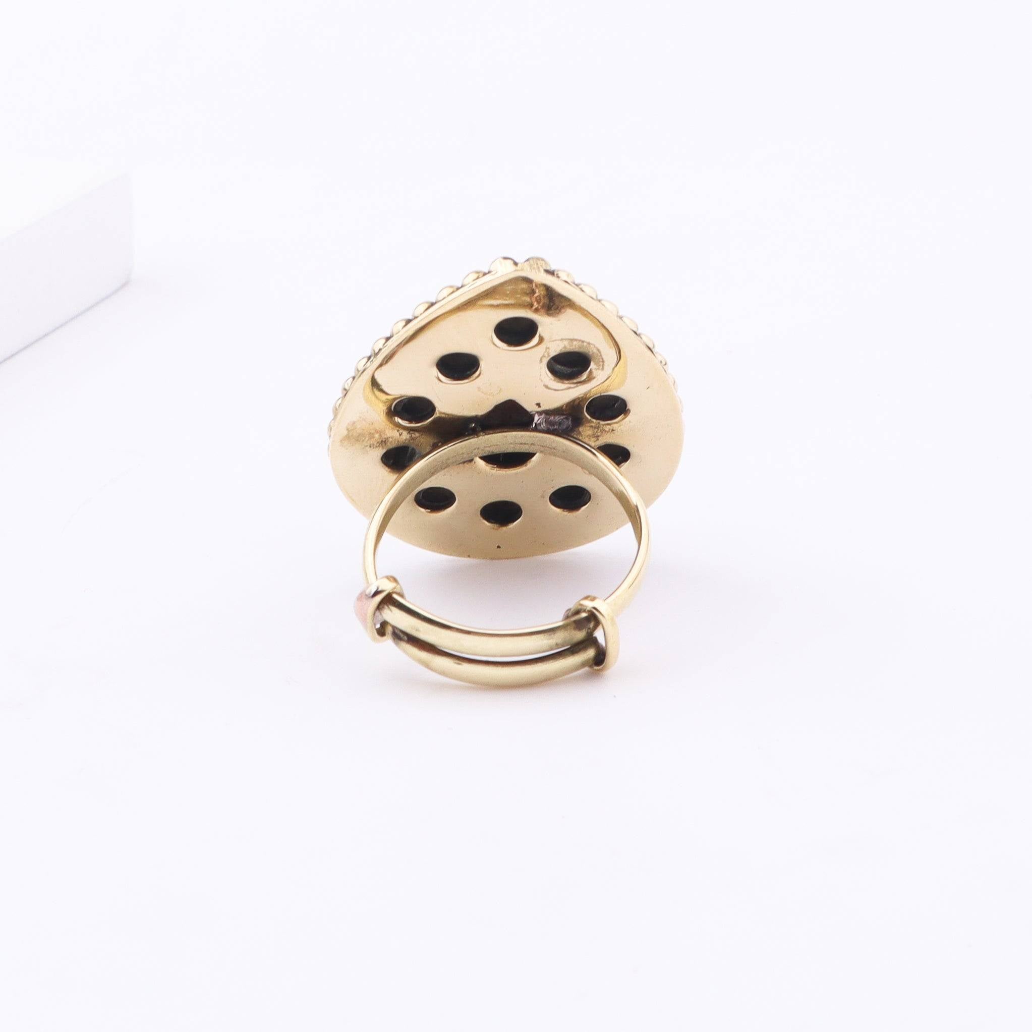 Angled view of a brass fashion ring highlighting its distinctive shape, structure, and polished brass finish