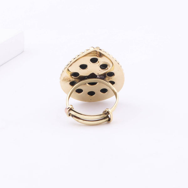 Angled view of a brass fashion ring highlighting its distinctive shape, structure, and polished brass finish