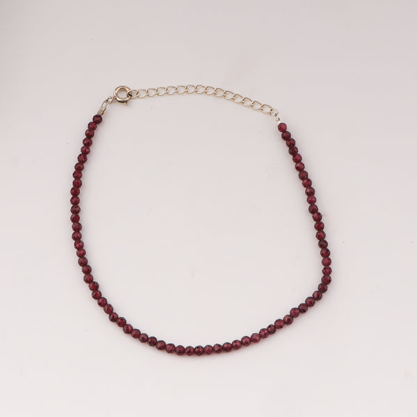 Close-up of garnet beaded anklet with adjustable silver chain