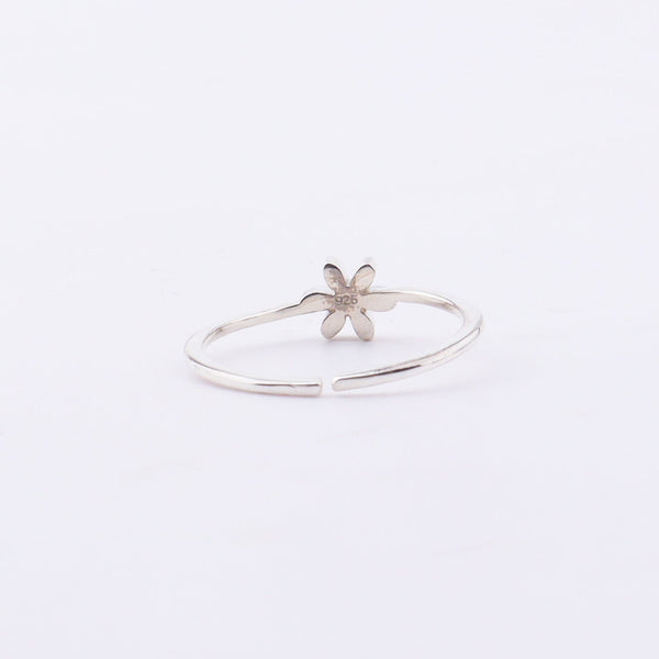 Close-up of white flower enamel ring on finger