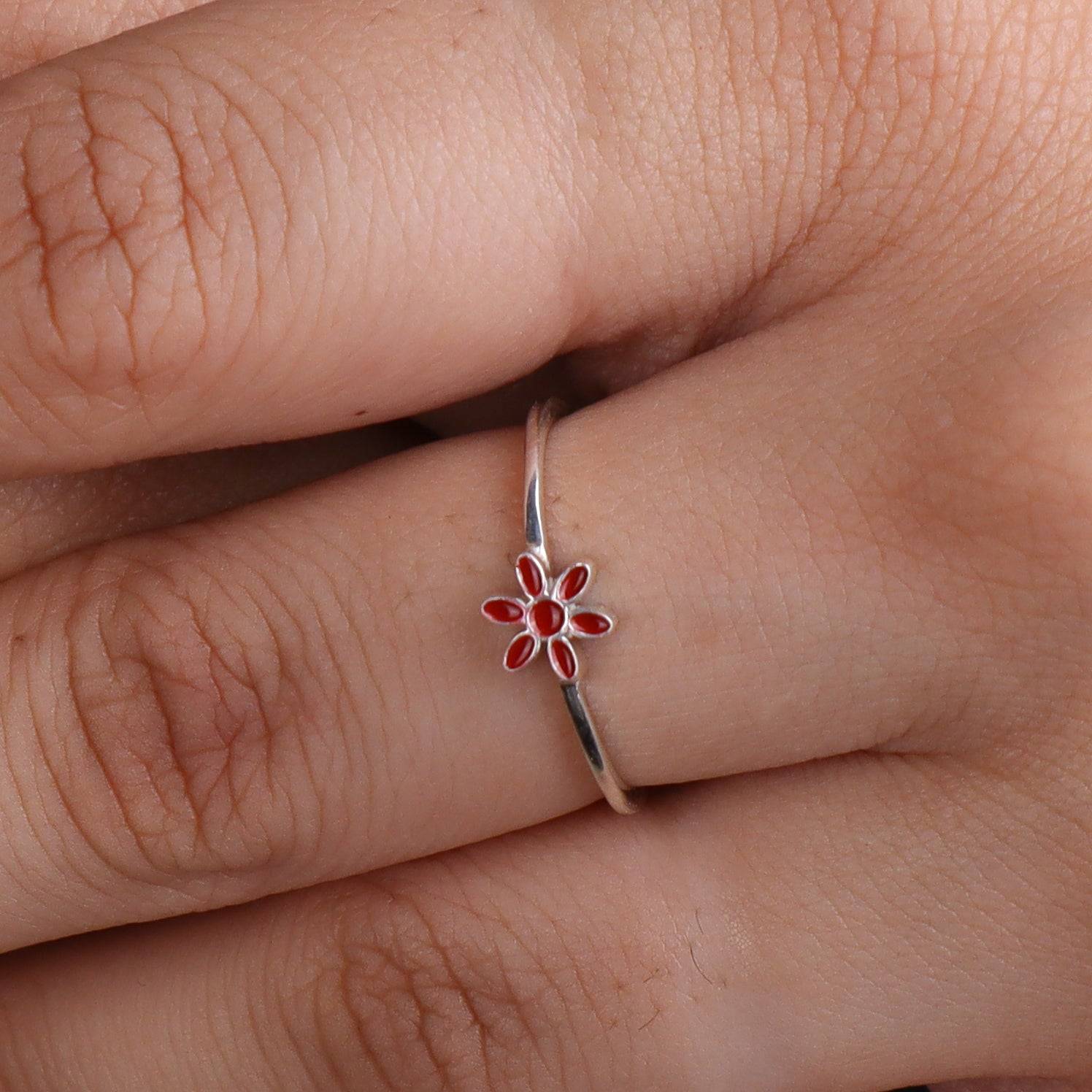 Silver flower ring with red enamel on finger