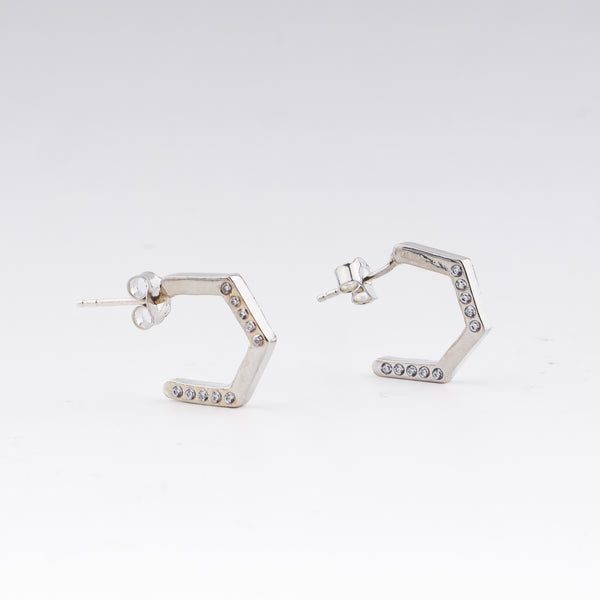 Silver hexagon hoop earrings with CZ stones on white background