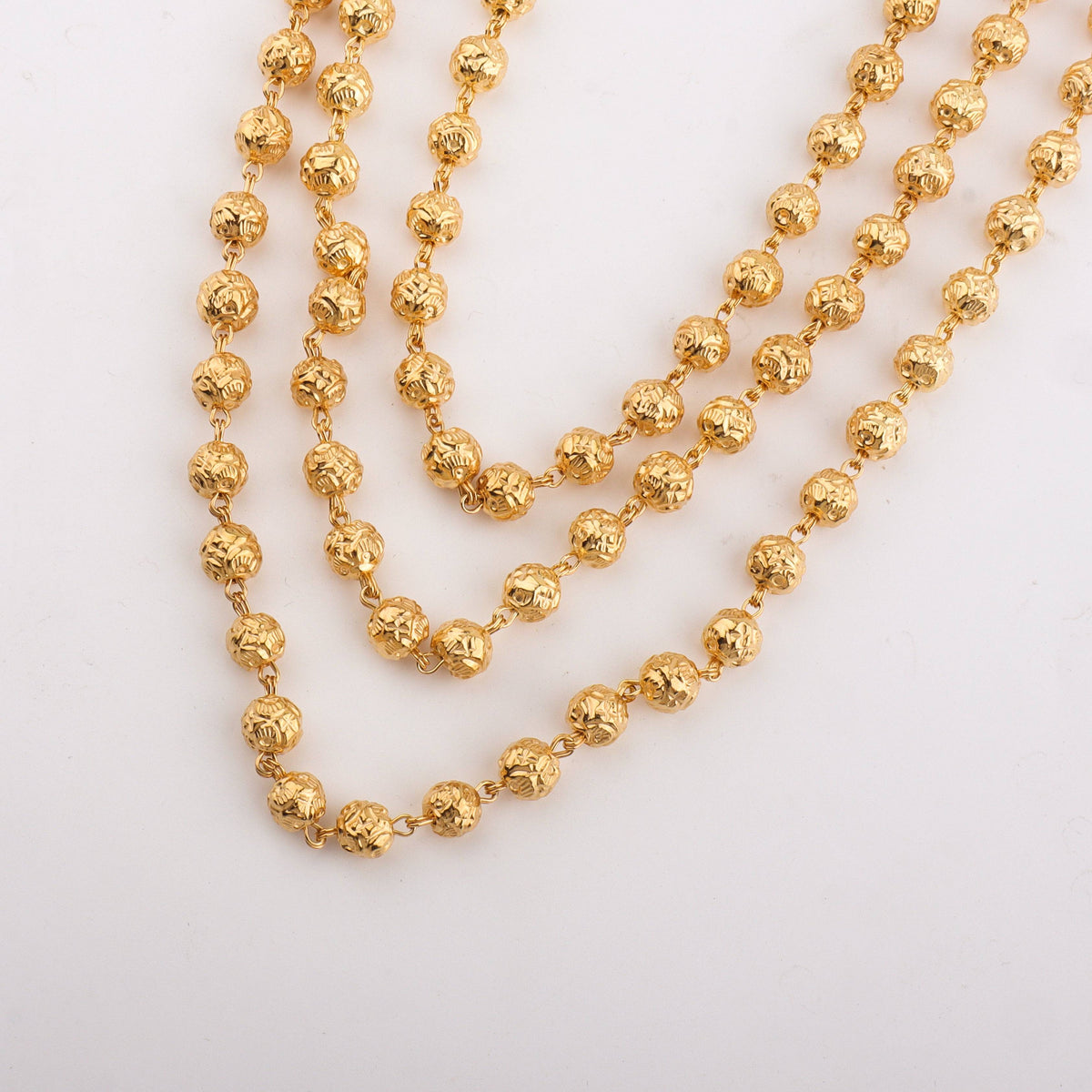 Close-up of gold beaded chain with textured round beads for traditional jewelry
