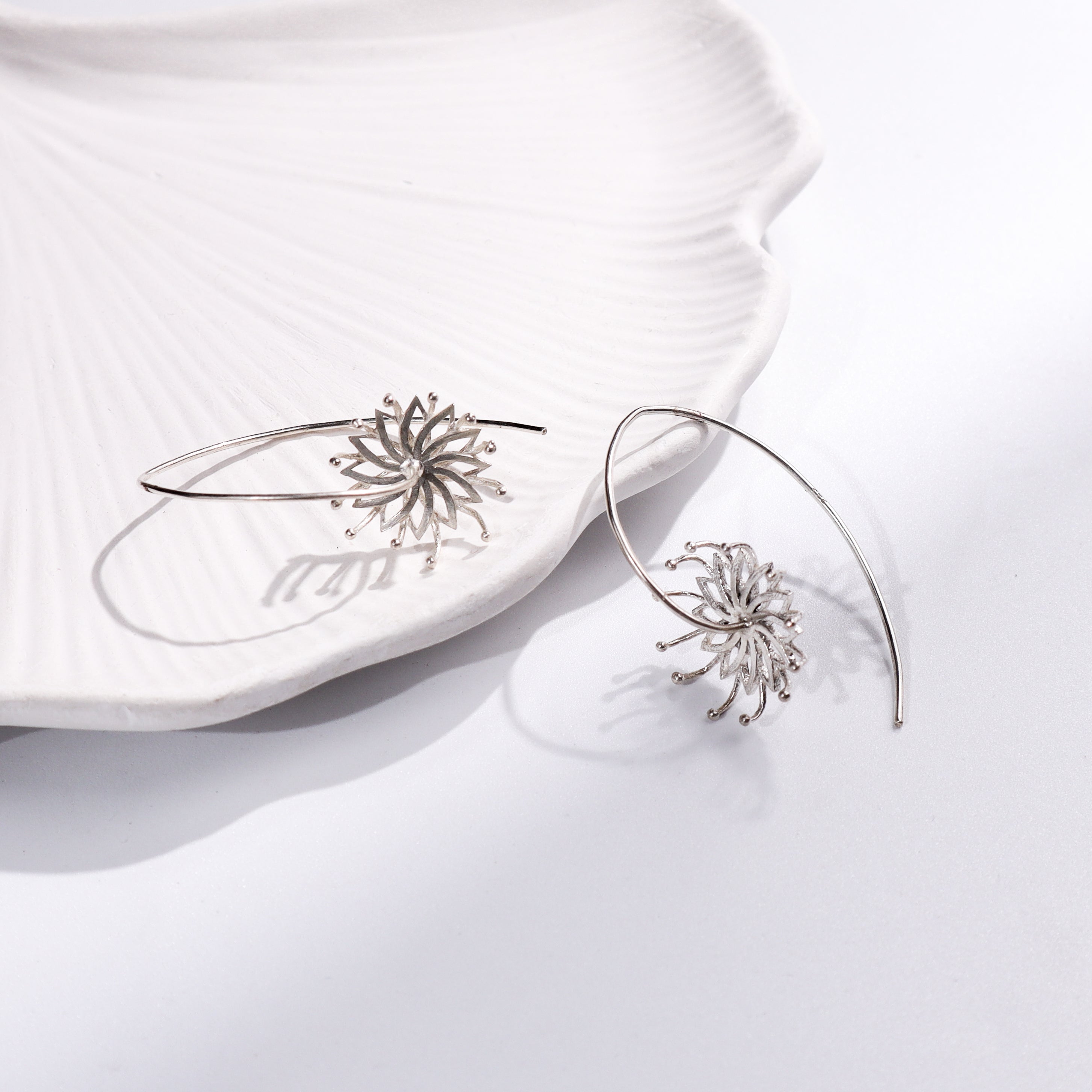 Bramhakamal Flower Earrings jewelry on white ceramic dish