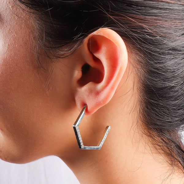 Close-up of silver hexagon earrings worn on ear