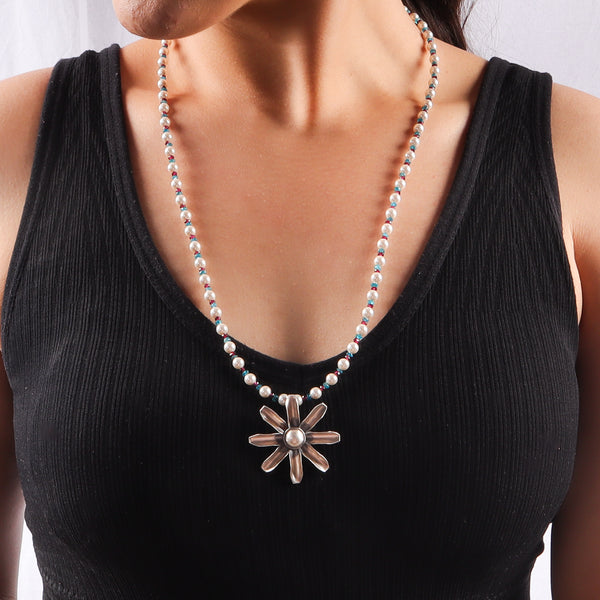 Beaded necklace with flower pendant, pearls, and colorful stones on model
